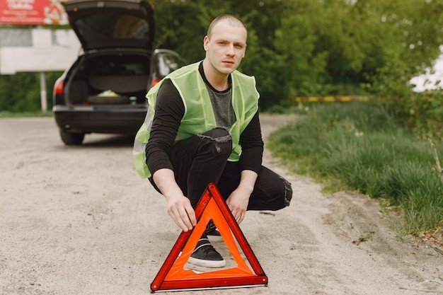 A man kneeling down on the ground next to an open car.