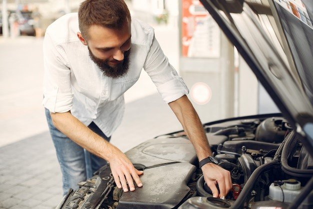 A man is working on the hood of his car.