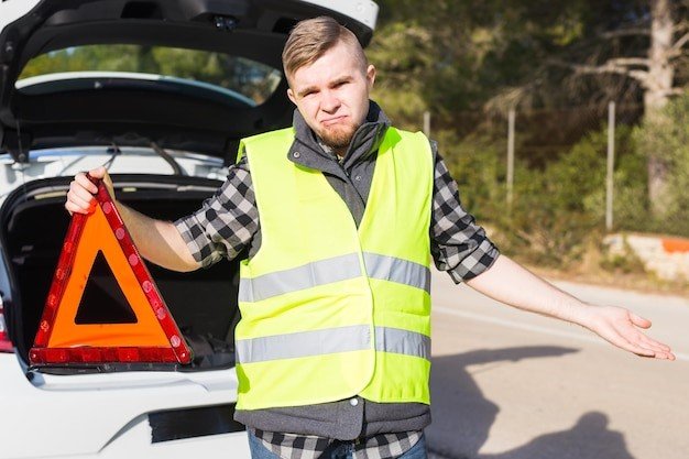 A man in yellow vest standing next to an open trunk.